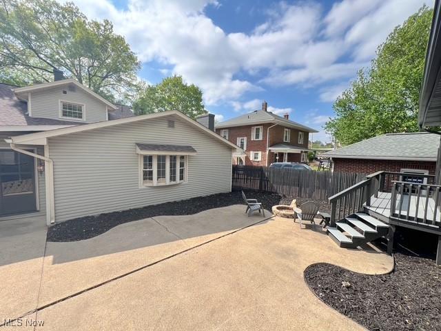 713 N Broadway St, New Philadelphia, OH 44663 - back of property featuring a fire pit, a wooden deck, a patio, and fence