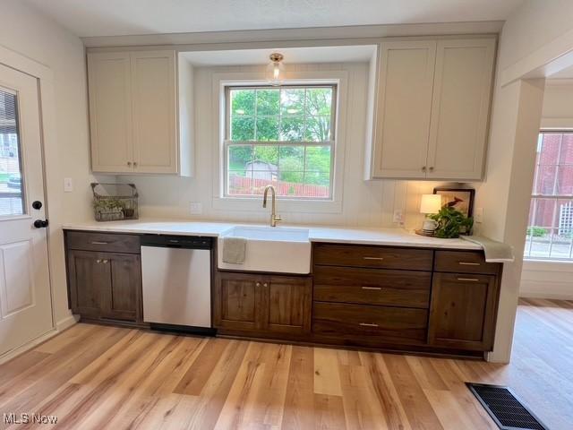 713 N Broadway St, New Philadelphia, OH 44663 - kitchen featuring dishwasher, a sink, light wood-style flooring, and light countertops