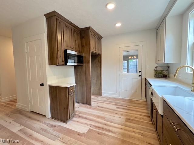 713 N Broadway St, New Philadelphia, OH 44663 - kitchen with stainless steel microwave, light wood-style floors, a sink, light countertops, and baseboards