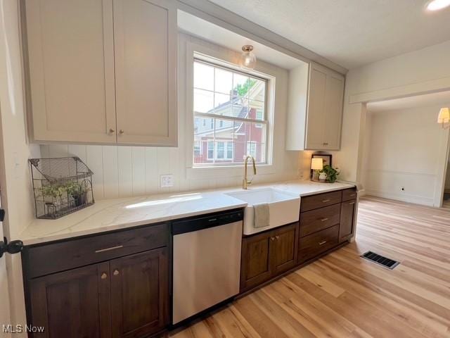 713 N Broadway St, New Philadelphia, OH 44663 - kitchen with stainless steel dishwasher, a sink, light wood-type flooring, and light stone counters