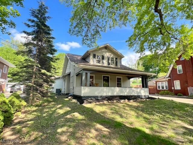 713 N Broadway St, New Philadelphia, OH 44663 - view of front facade featuring a porch, a front yard, and central AC