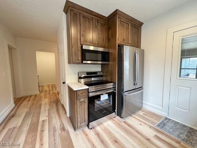 713 N Broadway St, New Philadelphia, OH 44663 - kitchen featuring stainless steel appliances, light wood-type flooring, baseboards, light countertops, and brown cabinets