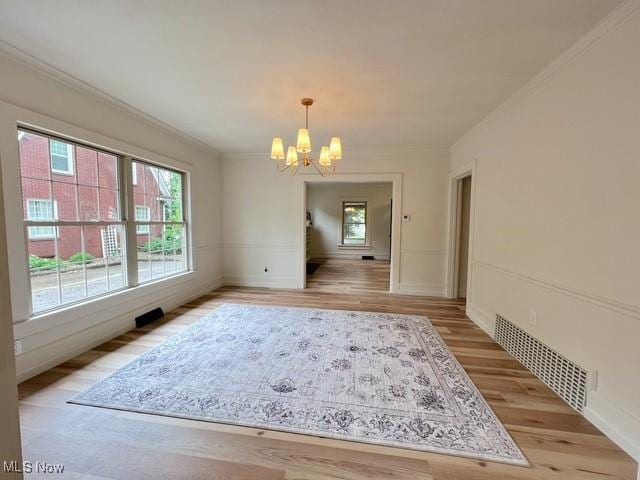 713 N Broadway St, New Philadelphia, OH 44663 - unfurnished dining area featuring a chandelier, light wood-style flooring, crown molding, and baseboards