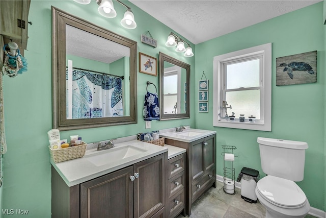 full bathroom with a textured ceiling, baseboards, toilet, and vanity
