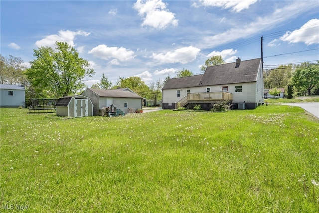 view of grassy yard featuring a shed, a deck, and an outdoor structure