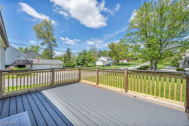 deck featuring a lawn, an outbuilding, a detached garage, and a residential view
