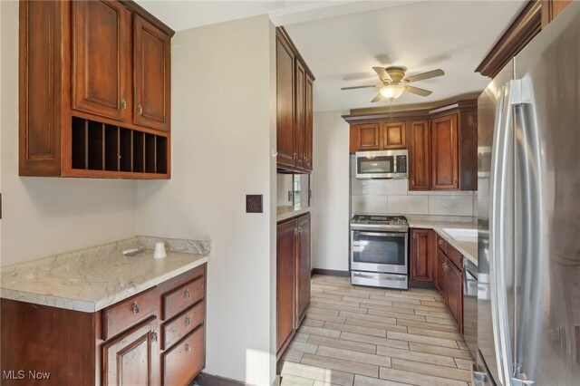 1540 Grand Park Ave, Akron, OH 44310 - kitchen featuring stainless steel appliances, a ceiling fan, light countertops, tasteful backsplash, and light wood-type flooring