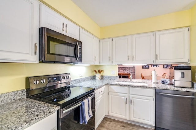 9942 Pebble Beach Cv, Reminderville, OH 44202 - kitchen featuring stainless steel appliances, a sink, white cabinetry, light stone countertops, and light wood finished floors