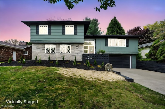 2162 Daniels Ave, Akron, OH 44312 - split level home with stone siding, concrete driveway, a yard, and a garage
