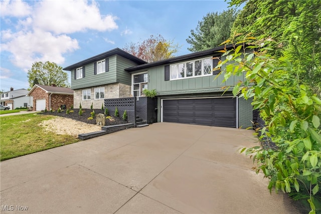 2162 Daniels Ave, Akron, OH 44312 - tri-level home featuring an attached garage, concrete driveway, board and batten siding, and stone siding