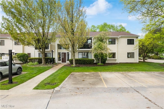 townhome / multi-family property featuring a front lawn and uncovered parking