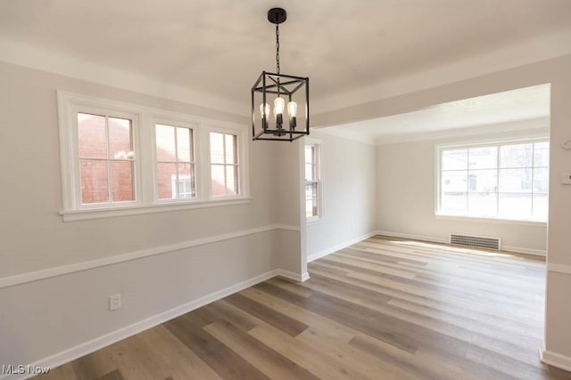 unfurnished dining area featuring a chandelier, wood finished floors, and baseboards