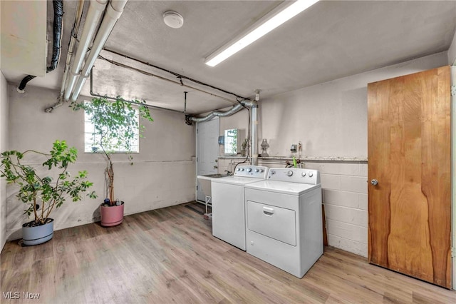 laundry room with independent washer and dryer, light wood finished floors, and concrete block wall