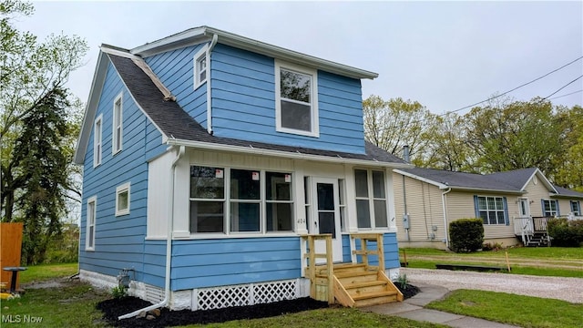 view of front facade featuring roof with shingles and a front lawn