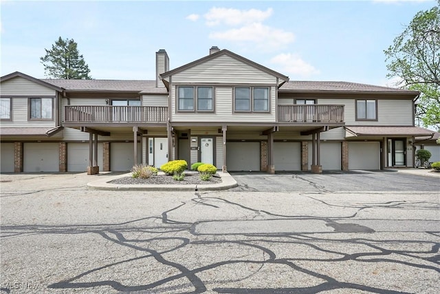 2889 Charing Cross Rd NW, Canton, OH 44708 - view of property featuring a balcony, an attached garage, brick siding, a chimney, and driveway