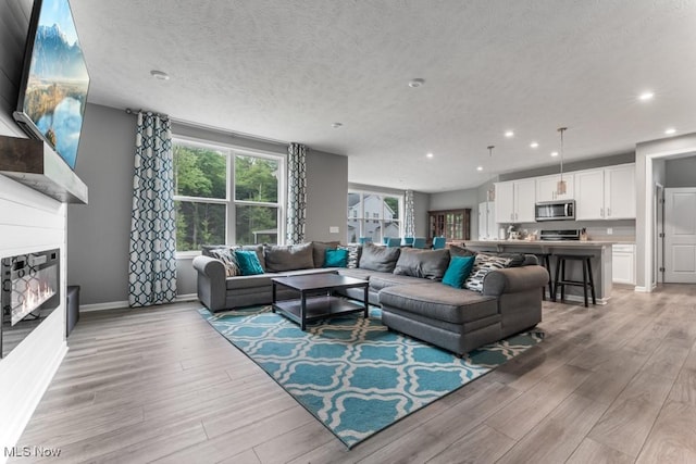 1726 Cobham Ln, Wadsworth, OH 44281 - living room with recessed lighting, light wood finished floors, a textured ceiling, a fireplace, and baseboards