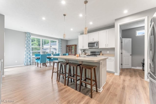 1726 Cobham Ln, Wadsworth, OH 44281 - kitchen with stainless steel appliances, an island with sink, light countertops, white cabinetry, and baseboards