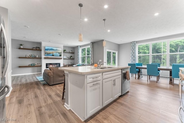 1726 Cobham Ln, Wadsworth, OH 44281 - kitchen featuring a sink, stainless steel appliances, light wood-style floors, white cabinets, and a kitchen island with sink