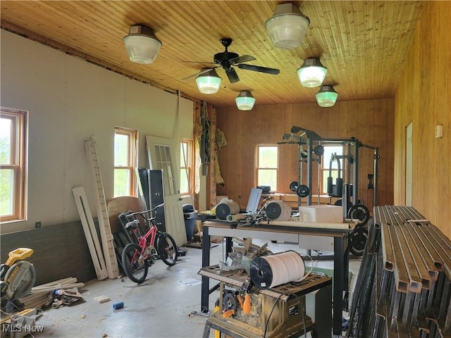 misc room featuring unfinished concrete floors, wooden walls, wood ceiling, and ceiling fan