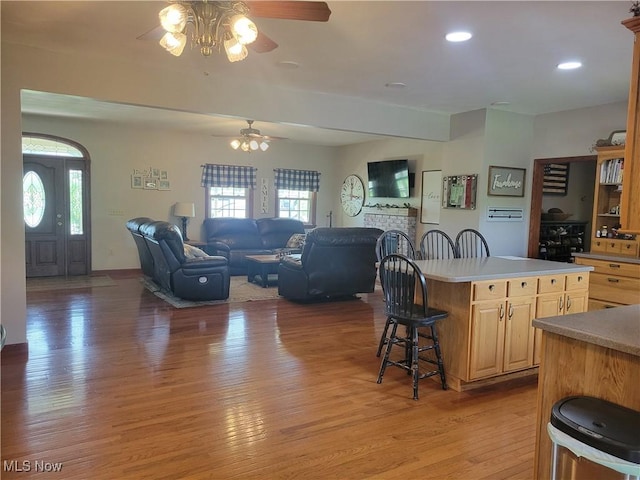 kitchen featuring a ceiling fan, light wood finished floors, a breakfast bar area, light brown cabinetry, and a kitchen island
