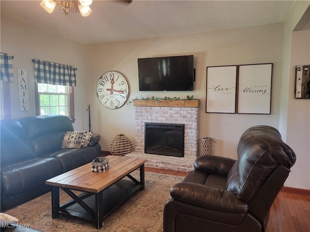 living room with ceiling fan, a brick fireplace, and wood-type flooring