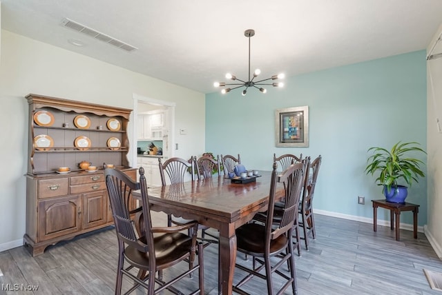 613-3 Fairington Oval, Aurora, OH 44202 - dining room featuring a chandelier, light wood-style flooring, and baseboards