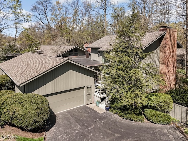 613-3 Fairington Oval, Aurora, OH 44202 - view of front of home featuring a shingled roof, driveway, an attached garage, and a chimney