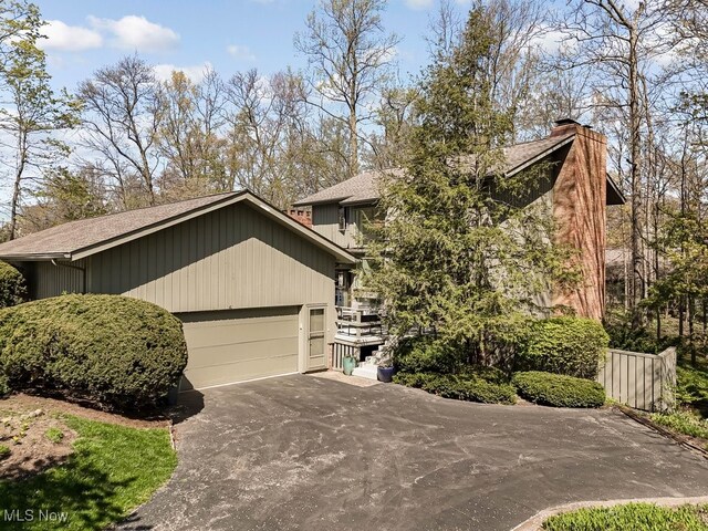 613-3 Fairington Oval, Aurora, OH 44202 - view of front facade with a shingled roof, a chimney, a garage, and driveway