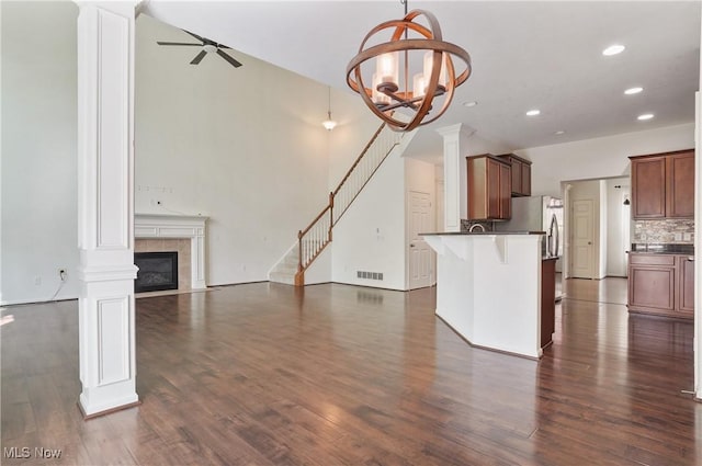 unfurnished living room featuring dark wood-style flooring, a ceiling fan, a tile fireplace, recessed lighting, and stairs