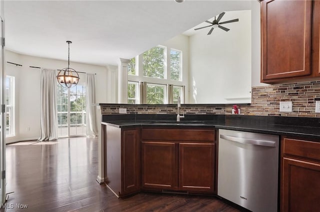 kitchen featuring dishwasher, a sink, dark countertops, and plenty of natural light
