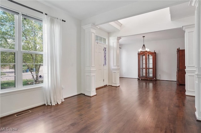 spare room with ornate columns, dark wood-style flooring, and baseboards