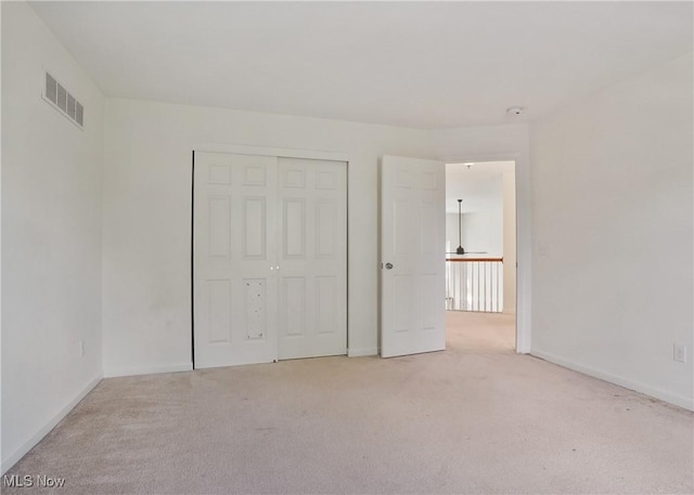 unfurnished bedroom with light carpet, baseboards, and a closet