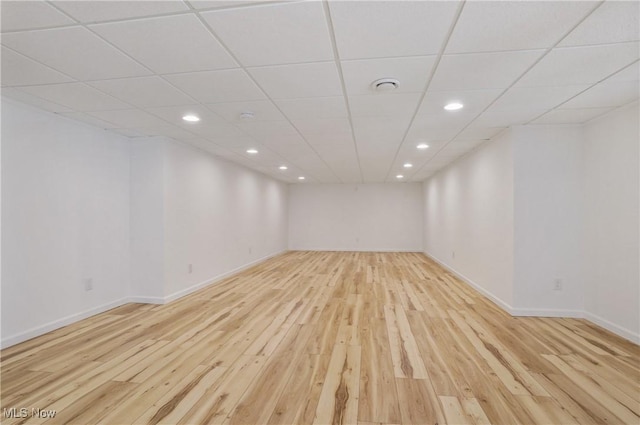 finished below grade area with light wood-type flooring, recessed lighting, baseboards, and a drop ceiling