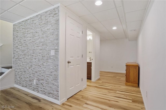 hallway featuring a paneled ceiling, light wood-type flooring, baseboards, and recessed lighting