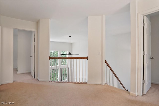 hall with carpet, baseboards, and an upstairs landing