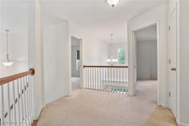corridor with a chandelier, light carpet, an upstairs landing, and baseboards