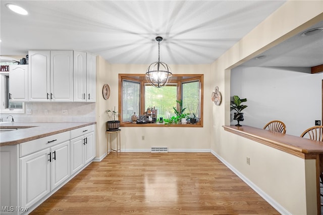 16538 S White Oaks Dr, Strongsville, OH 44136 - kitchen with light wood finished floors, white cabinetry, light countertops, and pendant lighting