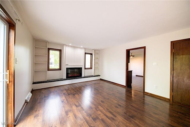 1537 Plantation Dr, Hudson, OH 44236 - unfurnished living room with baseboard heating, built in features, wood finished floors, a glass covered fireplace, and baseboards