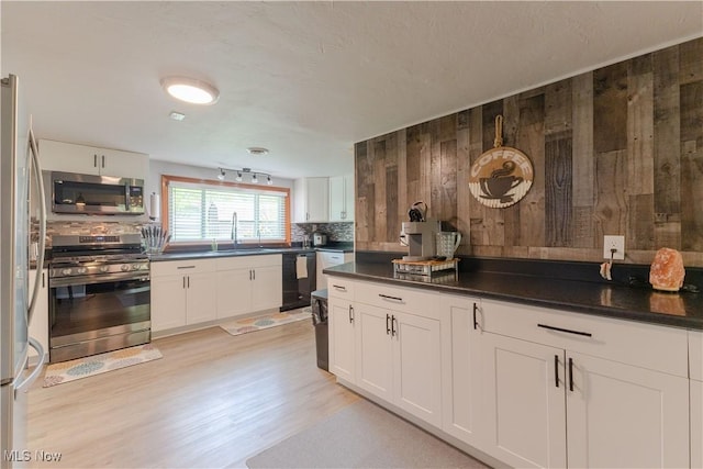 274 2nd St, Lake Milton, OH 44429 - kitchen with appliances with stainless steel finishes, decorative backsplash, a sink, white cabinetry, and wooden walls