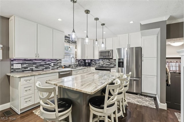 5610 Charles Ave, Parma, OH 44129 - kitchen featuring stainless steel appliances, a sink, a kitchen breakfast bar, white cabinetry, and decorative backsplash