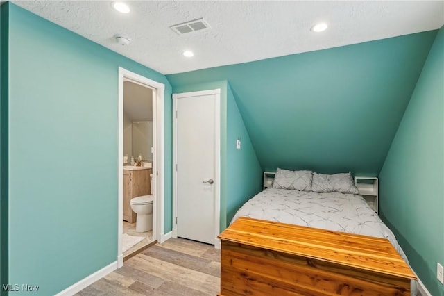 5610 Charles Ave, Parma, OH 44129 - bedroom featuring light wood-style flooring, connected bathroom, recessed lighting, baseboards, and a textured ceiling
