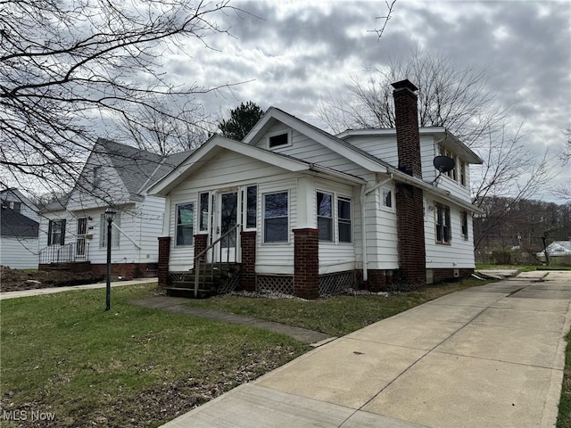view of front of house featuring a chimney, entry steps, and a front yard