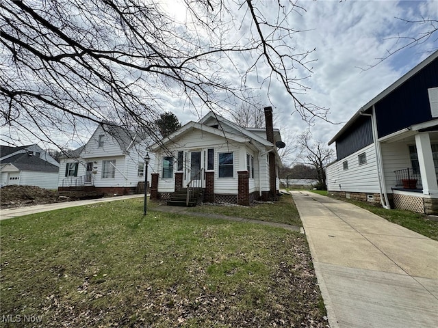 view of front of house with a chimney, a front yard, and concrete driveway