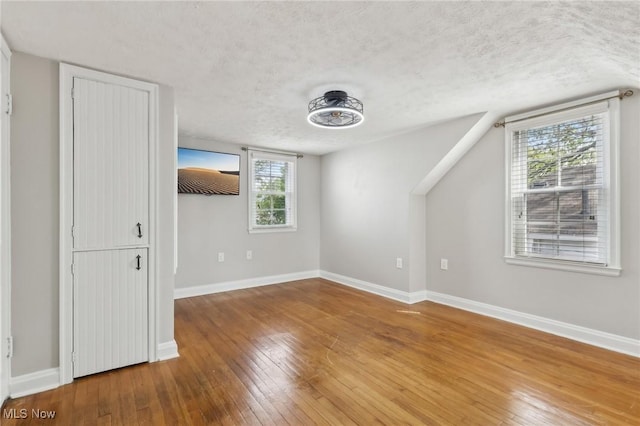 unfurnished bedroom featuring a textured ceiling, hardwood / wood-style flooring, and baseboards