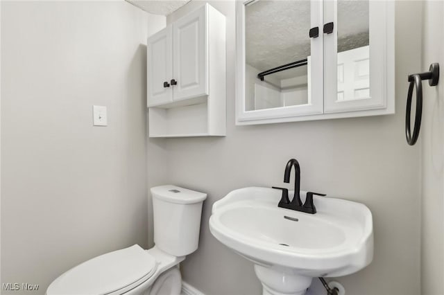 half bath featuring a sink, toilet, and baseboards