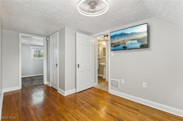 unfurnished bedroom with hardwood / wood-style floors, a textured ceiling, and baseboards