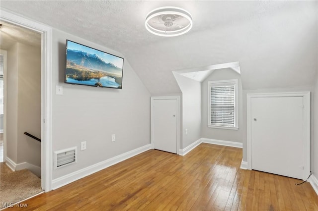 bonus room featuring light wood finished floors, baseboards, and vaulted ceiling