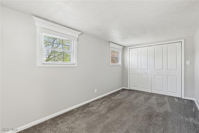 unfurnished bedroom featuring dark carpet, baseboards, a closet, and a textured ceiling