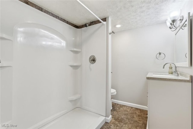 full bathroom featuring a shower stall, vanity, baseboards, toilet, and a textured ceiling