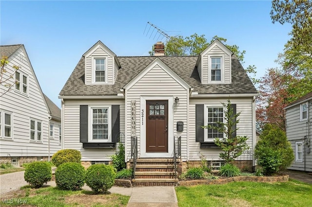 cape cod-style house featuring entry steps, a shingled roof, and a chimney